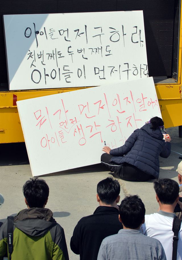 한 세월호 실종자 가족이 24일 전남 진도 팽목항에서 실종된 학생들의 구조를 우선해 달라는 내용의 글을 쓰고 있다. 진도=왕태석기자 kingwang@hk.co.kr