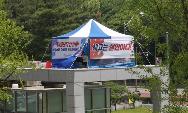 13일 오후 서울 노원구 서울여자대학교 정문 경비실 지붕에서 대학 경비노동자들이 학교측의 정리해고에 반발, 천막농성을 하고 있다. <연합뉴스>