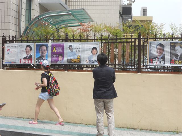 한 유권자가 대구 수성구청 담장에 게시된 선거용 벽보를 유심히 살펴보고 있다.