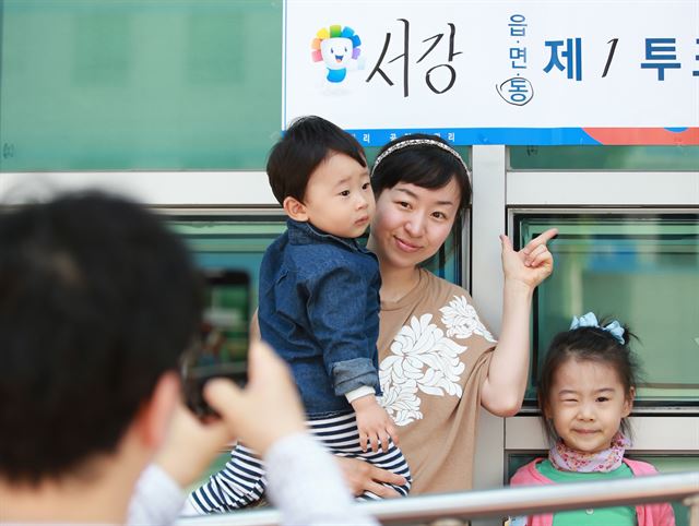 전국동시지방선거일인 4일 오전 서울 마포구 서강동 서강동주민센터에서 한 가족이 투표를 마친 뒤 투표소 앞에서 인증사진을 촬영하고 있다. 연합뉴스