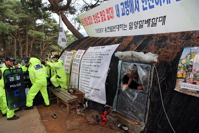 11일 오전 경남 밀양시 부북면 장동마을 입구 움막에서 765㎸ 송전탑 공사에 반대하며 장기간 농성을 벌이던 주민을 경찰이 제압하고 있다. 밀양시는 이날 오전 6시 행정대집행 영장을 주민과 반대대책위원회에 전달하고 농성장을 강제 철거했다.연합뉴스.