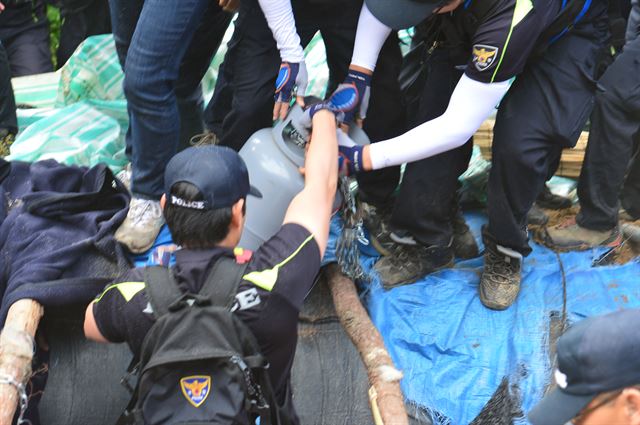 11일 오전 경남 밀양시 부북면 위양리 평밭마을 129번 송전탑 농성장 구덩이에서 LG가스통이 발견되자 경찰이 황급히 구덩이 밖으로 옮기고 있다. 뉴시스