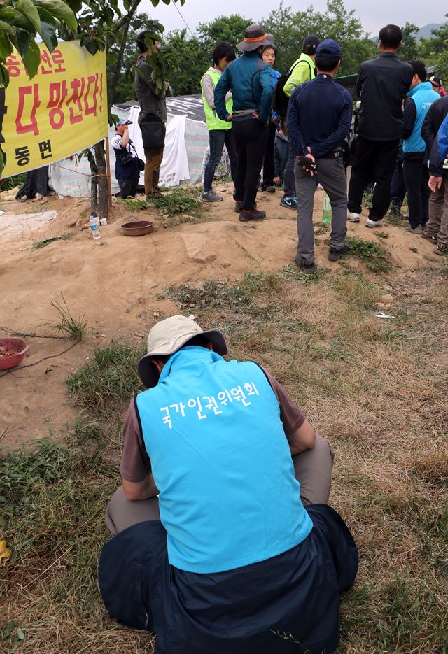 11일 경남 밀양시 상동면 고답마을 115번 송전탑 공사현장에서 765㎸ 송전탑 공사에 반대하는 주민과 경찰이 서로 격한 대화를 나누는 동안 국가인권위원회 관계자가 한가하게 바닥에 앉아 있다. 국가인권위는 이날 현장에서 소극적인 대처로 비판을 받았다. 연합뉴스