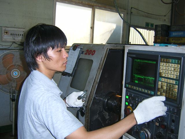 자신이 관리하는 선반CNC 기계를 살펴보고 있는 베트남 출신 이주노동자 닝씨. 한국일보 자료사진