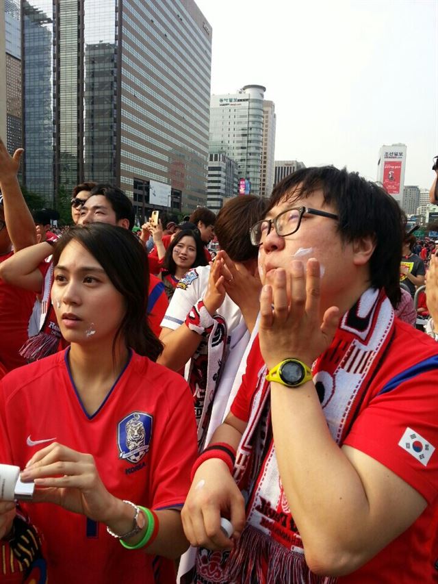 서울 광화문 광장에서 월드컵 응원에 나선 시민들이 전반전이 득점 없이 끝난 후 얼굴에 선크림을 바르며 휴식을 취하고 있다.