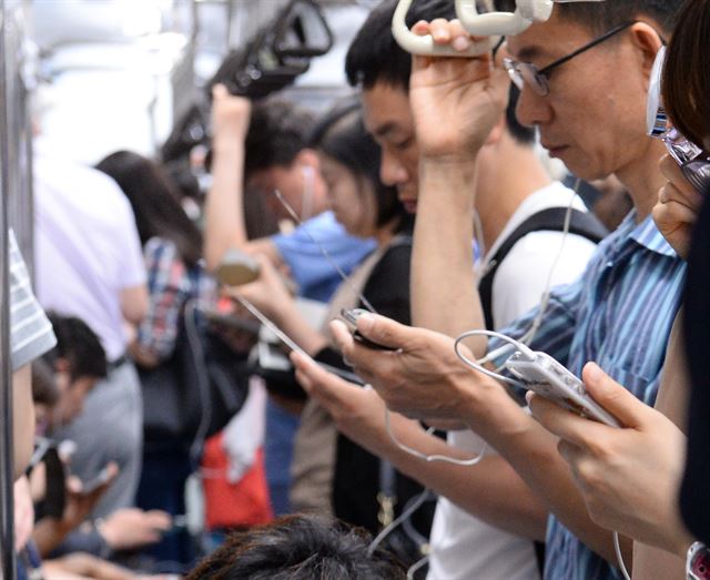 브라질 월드컵 조별예선 한국 대 러시아의 경기가 열린 18일 오전 서울 지하철 4호선 사당행 열차안에서 시민들이 스마트폰을 통해 경기 중계를 시청하고 있다. 뉴시스