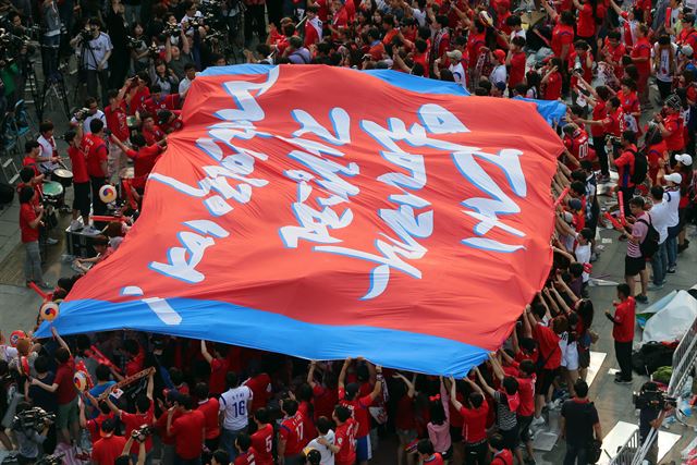 18일 브라질월드컵 한국과 러시아의 경기를 응원하기 위해 서울 광화문 광장에 모인 축구팬들이 응원 문구가 담긴 대형 현수막을 펼치고 있다. 연합뉴스