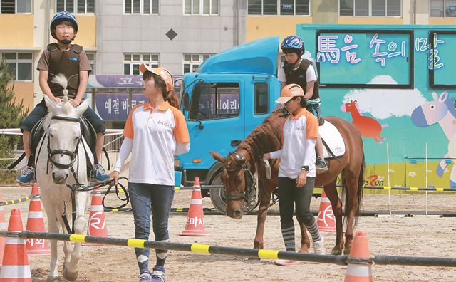 지난 12일 안양 덕천초교에서 열린 '마음속의 말' 행사에서 초등생들이 승마체험을 하고 있다. 한국마사회 제공 /2014-06-19(한국스포츠)