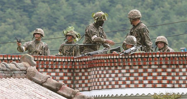 21일 오후 동부전선 최전방 GOP에서 초병이 동료 병사들을 향해 소총을 난사한 뒤 무장 탈영을 하는 사고가 발생해 강원도 고성 일대에 진돗개 '하나'가 발령 된 가운데, 22일 오후 사건 현장과 가장 가까운 것으로 알려진 강원도 고성군 거진읍 명파리 인근에서 교전이 일어나자 무장한 군인들이 민가 옥상 위에서 경계를 서고 있다. 연합뉴스