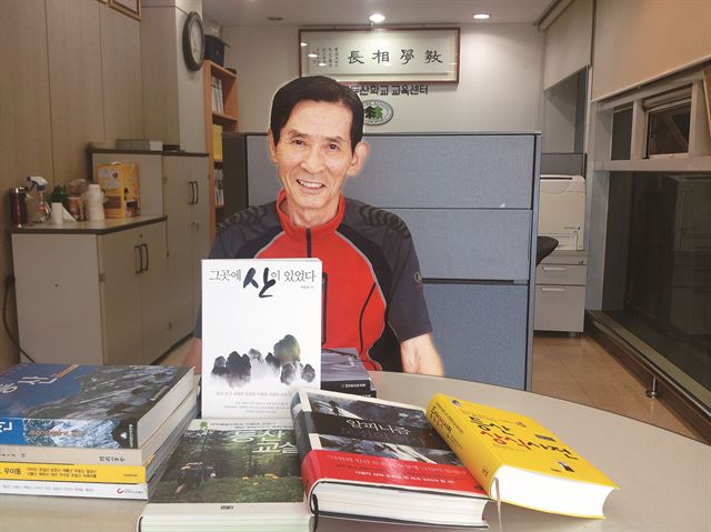 이용대 코오롱 등산학교 교장이 24일 서울 도봉구 코오롱 등산학교 교육센터에서 ‘그곳에 산이 있었다’ 등 자신의 저서들을 내보이고 있다. 뒷벽에 걸린 ‘교학상장(敎學相長)’은 “학생은 스승에게 배우면서 성장하고, 스승은 학생을 가르치며 진보한다”는 뜻으로, 이 교장이 가장 좋아하는 글귀다.