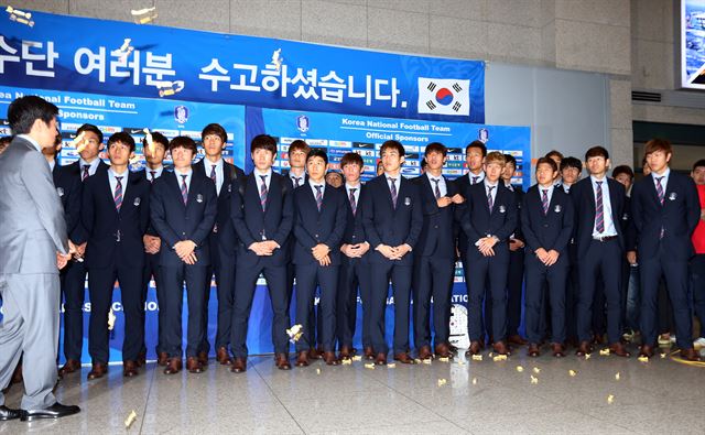 한국 축구 대표팀 선수들이 30일 오전 인천공항을 통해 귀국, 기념촬영을 위해 대기하던 중 일부 팬이 대표팀의 부진을 질타하며 호박엿 맛 사탕을 던지자 당혹스러워하고 있다. 홍명보 감독이 이끄는 대표팀은 2014 브라질월드컵에서 H조 꼴찌로 조별리그에서 탈락했다. 연합뉴스