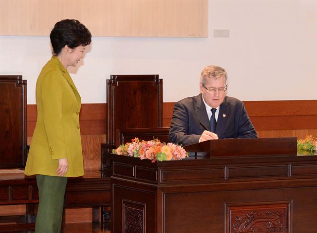 한국을 국빈 방문한 브로니스와프 코모로프스키 폴란드 대통령이 2013년 10월 22일 오후 청와대에서 열린 정상회담에 앞서 박근혜 대통령이 지켜보는 가운데 방명록에 서명하고 있다. /고영권기자 youngkoh@hk.co.kr