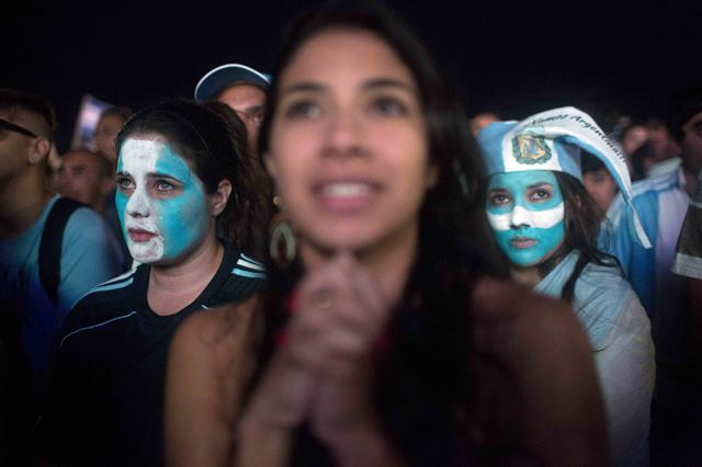 [PAP20140714167001034] Fans of the Argentina national soccer team watch Germany's victory over their team as a Brazilian fan, center, roots for Germany as they watch the final of the World Cup, on the beach in Copacabana, Rio de Janeiro, Brazil, Sunday, July 13, 2014. (AP Photo/Rodrigo Abd)