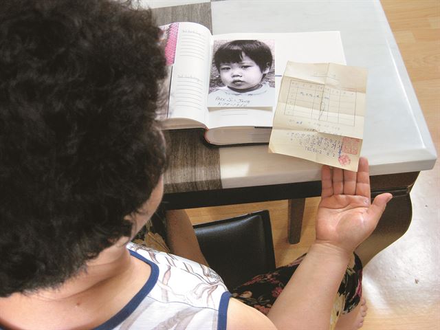 김정숙씨가 16일 경기도 자택에서 수정씨가 입양될 당시 사진과 고아원에 아이를 맡겼을 때 받았던 인수증을 꺼내 보고 있다. 모녀의 만남은 수정씨가 중앙입양원 인터넷 홈페이지에 입양 당시의 본인 사진과 함께 가족을 찾는다는 글을 올려 놓은 것을 김정숙씨 조카가 발견해 이뤄졌다.