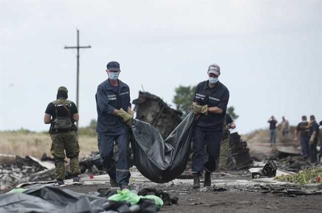 우크라이나 구조당국 대원들이 20일 말레이시아항공 MH17편 여객기 피격 추락 현장인 그라보보 인근에서 희생자 시신이 담긴 포대를 옮기고 있다. 그라보보=AP 연합뉴스