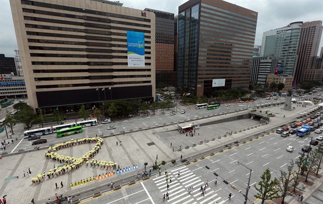 22일 오전 서울 광화문광장에서 열린 '위험사회를 멈추는 시민행동 퍼포먼스'에 참여한 세월호참사 국민대책회의와 핵없는사회를위한공동행동 등 시민단체 회원들이 노란 우산을 쓴 채 리본 모양을 만들고 있다. 세월호 참사 100일을 앞두고 벌인 퍼포먼스를 통해 이들은 참사가 반복되지 않도록 명확한 진상 규명을 할 것과 세월호 특별법을 제정할 것을 요구했다. 연합뉴스