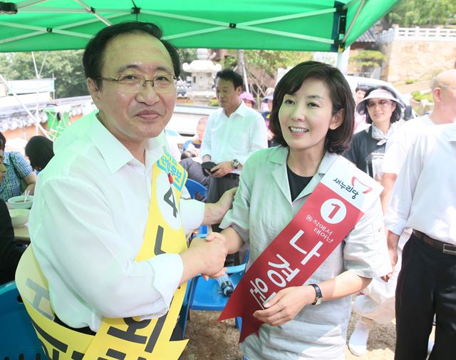 서울 동작을 국회의원에 도전하는 새누리당 나경원 후보(오른쪽)와 정의당 노회찬 후보가 27일 서울 동작구 흑석동 달마사에서 만나 인사하고 있다. 연합뉴스