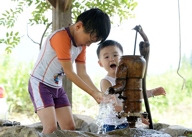 경남 지역에 폭염주의보가 발효된 30일 거창군 북상면 소정리 덕유산 한옥학교 우물펌프에서 어린이들이 더위를 식히고 있다.연합뉴스