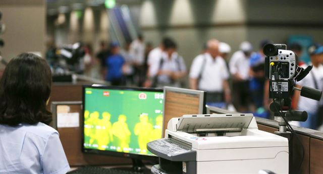 국립김해검역소 직원들이 김해공항 입국장에서 에볼라 바이러스를 차단하기 위해 열감지카메라로 고열 증상 승객 여부를 살펴보고 있다. 연합뉴스