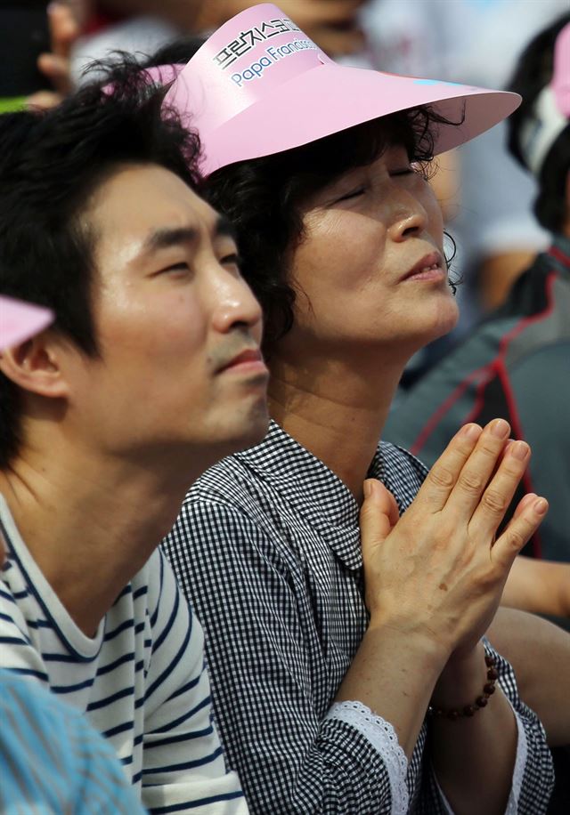 프란치스코 교황이 16일 오전 서울 광화문광장에서 열린 시복식에서 앞서 카퍼레이드를 하던 중 단식 농성 중인 세월호 유가족을 위로하는 모습을 대형 스크린으로 지켜보던 한 신자가 눈물을 흘리고 있다. 사진공동취재단