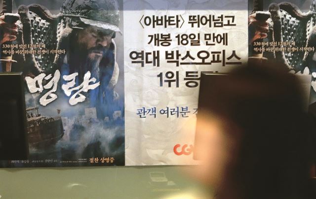 18일 서울 성동구의 한 복합상영관 매표소에 붙어 있는 '명량' 포스터 앞으로 극장을 찾은 관객이 지나가고 있다. 연합뉴스