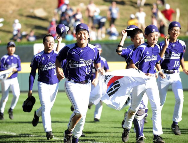 한국 리틀야구 대표팀이 25일 미국 펜실베이니아주 윌리엄스포트 라마데구장에서 열린 2014 리틀야구 월드시리즈 결승에서 미국을 8-4로 누르고 29년 만에 우승을 차지한 뒤 태극기를 들고 그라운드를 돌고 있다. 윌리엄스포트=AP 연합뉴스