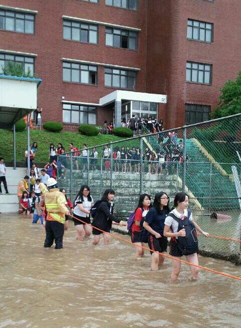 25일 집중호우로 침수된 부산 북구 구포동 양덕여중에서 학생들이 대피하고 있다. 연합뉴스