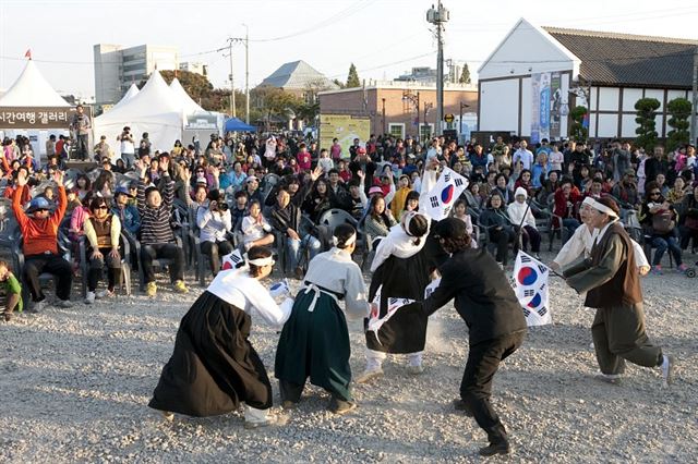 군산시간여행축제에 선보일 ‘남승재가 만드는 독립자금’의 쌀가마 나르기 체험 행사와 ‘쫓고 쫓기는 각시탈’ 공연 장면.