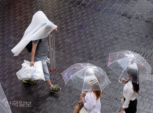 서울과 경기 일부지역에 소나기가 내린 12일 오후 서울 중구 명동을 찾은 한 시민이 발걸음을 재촉하고 있다. 김주영기자 will@hk.co.kr