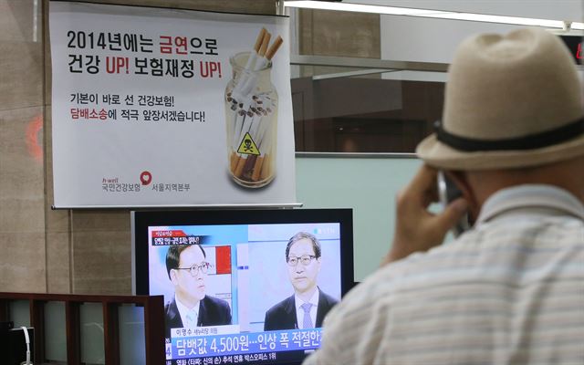 국민건강보험공단이 흡연 관련 질환으로 인한 진료비 손실을 부담하라며 담배회사들에게 낸 손해배상 소송이 열린 12일 서울 마포구 건보공단 민원실에 담배 소송을 알리는 홍보물 앞을 한 시민이 지나가고 있다. 연합뉴스