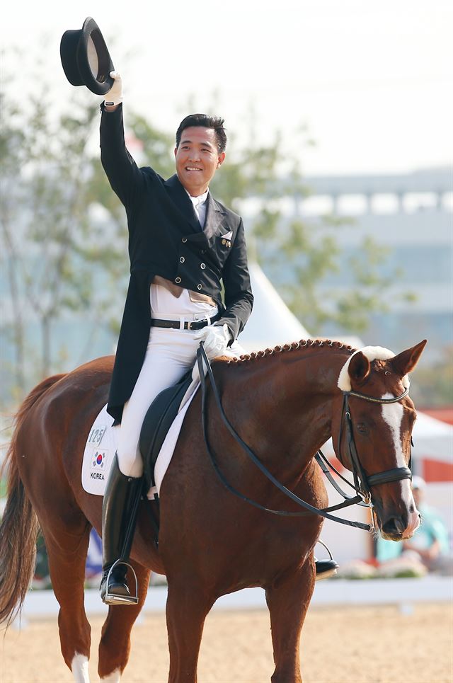 한국 승마 대표팀의 김동선(세종시승마협회)이 지난 20일 인천 드림파크 승마장에서 열린 마장마술 단체전에서 경기를 마친 관중에게 모자를 벗어 답례하고 있다. 김동선은 23일 대표팀 후배 황영식(세마대승마장)과 개인전 금메달을 놓고 경쟁한다. 인천=연합뉴스