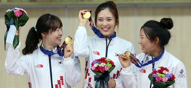 24일 인천 옥련국제사격장에서 열린 2014 인천 아시안게임 사격 여자 50m 소총 단체전에서 금메달을 획득한 여자사격팀 나윤경(왼쪽부터), 정미라, 음빛나가 시상대서 환호하고 있다. 연합뉴스