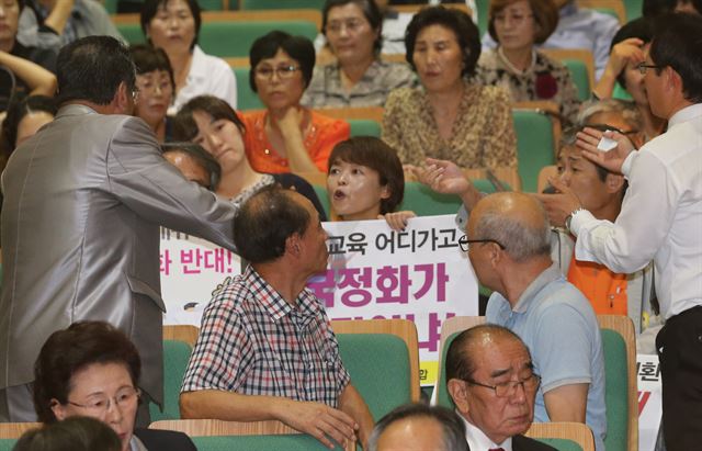 25일 서울 서울교대에서 열린 ‘문ㆍ이과통합형 교육과정 개정 추진에 따른 교과용도서 구분 기준(안) 정책연구 토론회’에서 교과서 국정화에 반대하는 피켓을 든 전국교직원노동조합 교사들에게 보수단체인 한국사국정화추진시민사회단체협의회 회원들이 항의하며 말다툼을 벌이고 있다. 연합뉴스