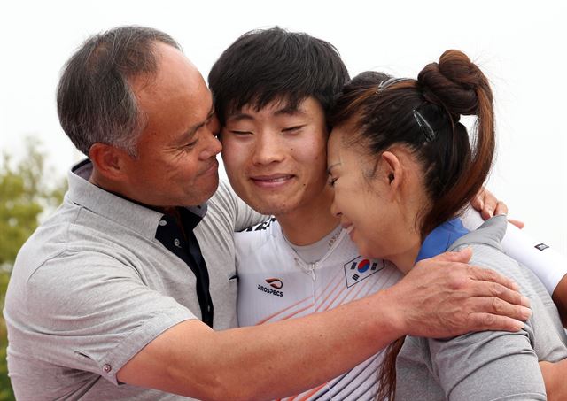 한국 사이클 대표팀 장경구가 28일 인천 송도사이클도로코스에서 열린 2014 인천 아시안게임 사이클 남자 개인도로 시상식에서 금메달을 목에 걸고 부모와 얼싸안고 기쁨을 나누고 있다. 연합뉴스