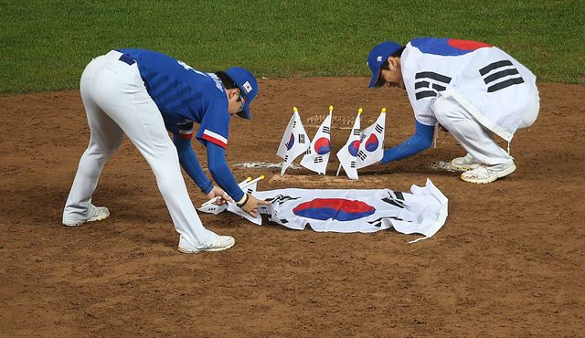 28일 인천 문학야구장에서 열린 2014 인천 아시안게임 야구 결승 한국과 대만의 경기에서 6대3으로 이겨 금메달을 차지한 한국 대표팀의 양현종(왼쪽)과 김광현이 마운드에 태극기를 꽂고 있다. 연합뉴스