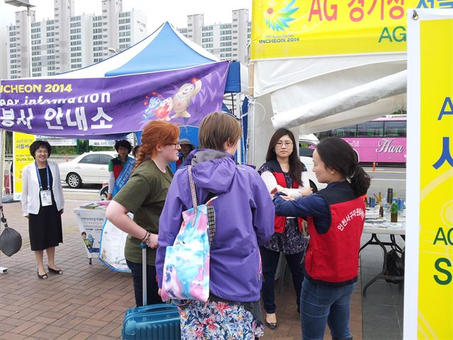 인천서구자원봉사센터 외국어 통역봉사단 이선영(맨 오른쪽)씨와 남윤희(오른쪽에서 두번째)씨가 24일 공항철도 검암역 앞 인천아시안게임 셔틀버스 승하차장에서 외국인들에게 길을 안내하고 있다. 서구자원봉사센터 제공