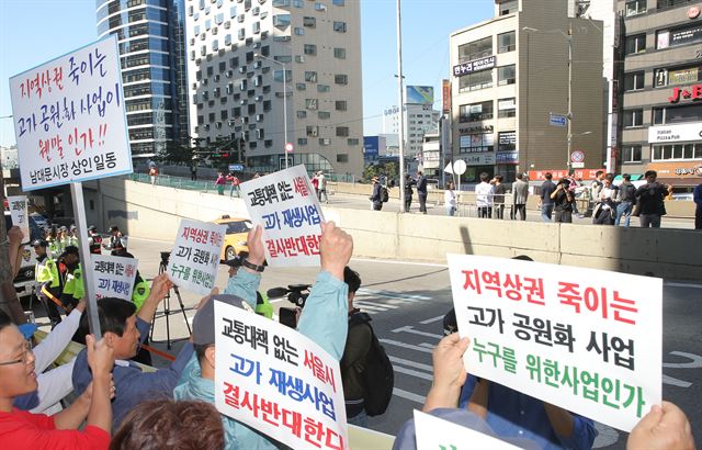 '서울역 고가도로 시민개방행사'가 열린 12일 고가 주변에서 남대문시장 상인과 지역주민들이 공원화에 반대하는 피켓을 들고 집회를 열고 있다. 연합뉴스