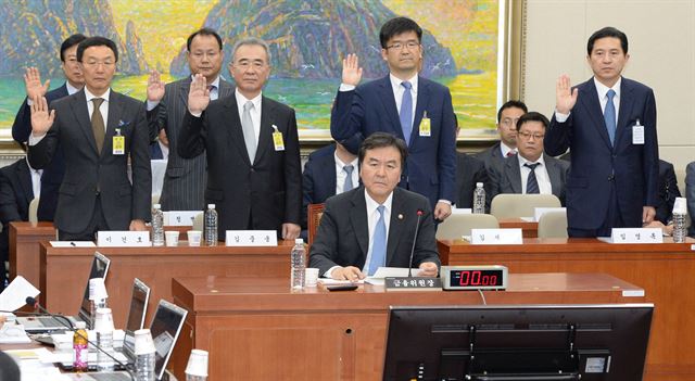 15일 국회에서 열린 정무위원회의 금융위원회에 대한 국정감사에서 임영록(오른쪽 첫 번째) 전 KB금융지주 회장과 이건호(왼쪽 첫 번째) 전 국민은행장 등 KB 사태 관련 증인들이 선서를 하고 있다. 신제윤 금융위원장은 증인들 앞에 앉아 의원들 질의에 답변할 준비를 하고 있다. 오대근기자 inliner@hk.co.kr