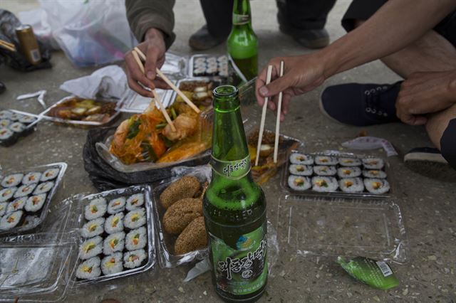 에릭 탈매지 AP통신 평양지국장이 북한 당국에서 이례적으로 장거리 자동차 이동을 허가해 평양을 출발, 일주일간 백두산을 다녀왔다고 밝힌 가운데, 사진은 6월 16일 황해북도 도로변에서 북한 주민들이 대동강 맥주를 놓고 점심을 나눠먹고 있는 모습. AP 연합뉴스