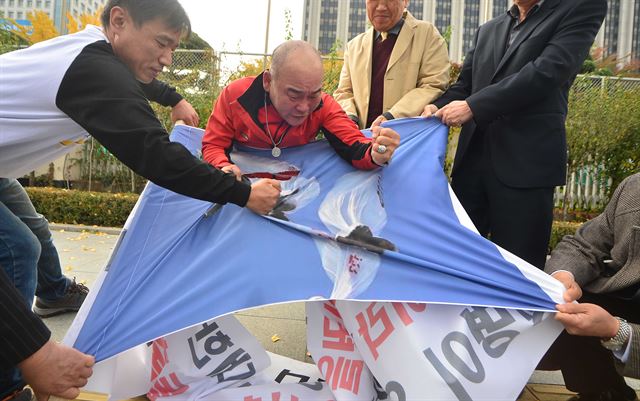 애국국민운동대연합 회원들이 31일 오후 정부서울청사 정문 앞에서 기자회견을 열고 대북전단 살포 사진이 새겨진 플래카드를 찢고 있다. 뉴시스