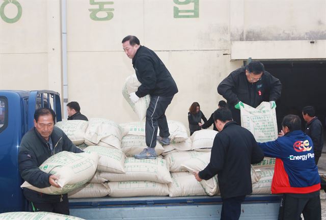 김영만 군수(가운데)가 지난 7일 청성면 화동리 곡물창고 앞에서 볏가마를 옮기고 있다. 옆에서 거드는 이들은 면사무소 직원이다. 옥천군 제공