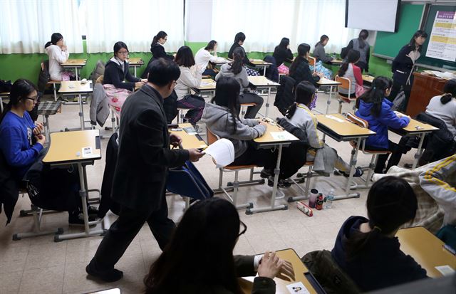 2015학년도 대학수학능력시험일인 13일 부산 수영구의 한 고등학교에 마련된 수능시험장에서 감독관이 시험에 앞서 수험생이 소지한 휴대전화 등 반입금지 물품을 수거하고 있다. 연합뉴스