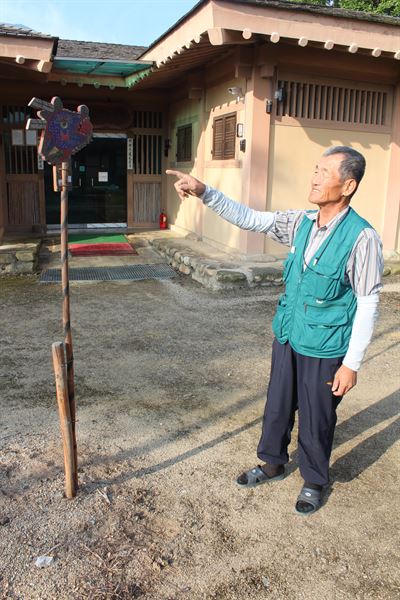 김정선씨가 깃대·기두 한 쌍을 땅에 꽂은 뒤 설명하고 있다.