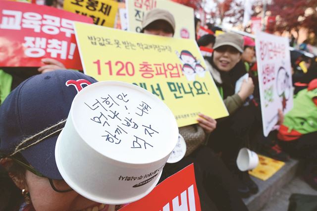 20일 서울역 광장에서 열린 학교비정규직 근로자 총파업 투쟁대회에서 한 참석자가 ‘한끼 밥 나눠 먹자’는 문구가 적힌 종이그릇을 머리에 쓰고, 급식비 지급과 방학 중 월급 지급 등을 요구하고 있다. 뉴시스