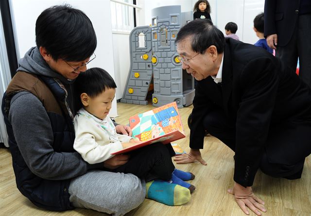 서울 강서구 가양동의 국내 첫 협동조합형 공동주택인 '이음채' 입주인들이 23일 박원순 서울시장 등을 초대하는 집들이를 가졌다. 이날 이음채 1층의 공동보육시설에서 동화책을 읽고 있는 아빠와 아이에게 박 시장이 다가가 인사말을 나누고 있다. 서울시청 제공