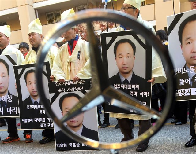 지난달 9일 오전 서울 강남구 압구정 신현대아파트 인근에서 ‘경비노동자 이만수 열사 추모 및 노동인권 쟁취 결의대회'를 마친 참석자들이 故 이만수 경비원이 분신한 아파트 단지내에서 상복과 고인의 영정을 들고 '입주자대표회의 사과'를 요구하며 구호를 외치고 있다. 뉴시스