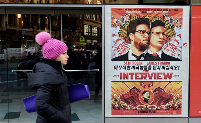 [PEP20141219035801034] <YONHAP PHOTO-0556> epa04534224 A woman walks past a poster for the film 'The Interview' outside of Regal Theater in New York, New York, USA, 18 December 2014. Sony Pictures, which was distributing the film, announced that it is not planning to release the film on Christmas Day, as was originally planned, due to terror threats against theaters. The film's narrative centers on an assassination of Kim Jong-un, the leader of North Korea, and that country has been tied to recent hacks of Sony Pictures internal servers. EPA/JUSTIN LANE/2014-12-19 06:17:13/