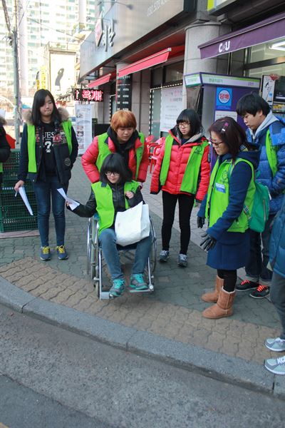 7일 인천 부평구 부평 1동 주민센터 인근 인도에서 학생들이 휠체어를 타고 밀면서 지도에 휠체어로 안전하고 편하게 이동할 수 있는 길을 표시하고 있다.