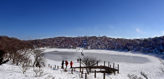 한라산 등반객들이 해발 1,300m 지점 사라오름 호수에서 풍광을 즐기고 있다. 상고대와 눈꽃이 풍성하다면 더없이 좋겠지만 태고의 원형으로 꽁꽁 얼어붙은 분화구만으로도 아쉬움을 달래기에 충분하다. 제주=최흥수기자 choissoo@hk.co.kr