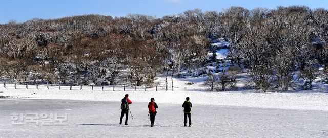 등산객들이 얼음으로 변한 사라오름 분화구 호수를 가로 질러 전망대로 향하고 있다.